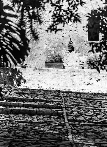 We walk into the courtyard, one of the typically Mallorcan clastras, with its cobblestone pavement surrounding a stone well at the center